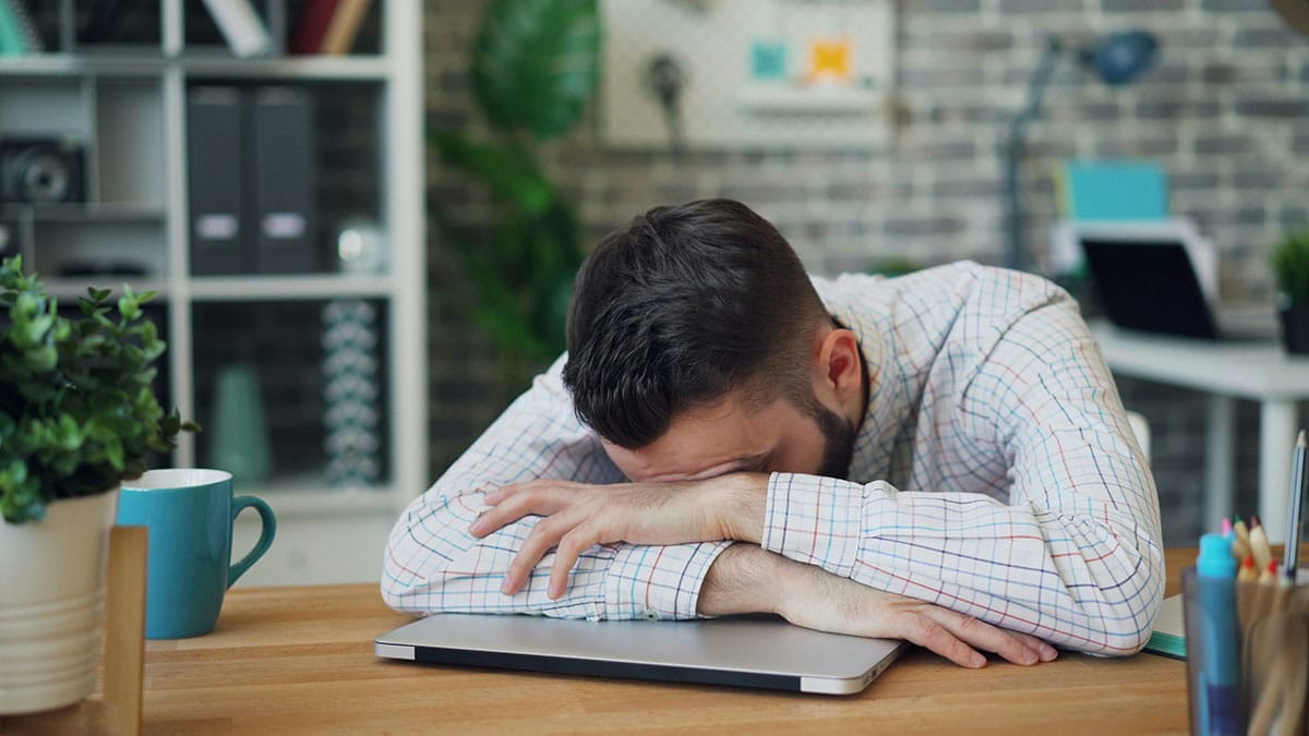 A man experiencing fatigue while working on his laptop
